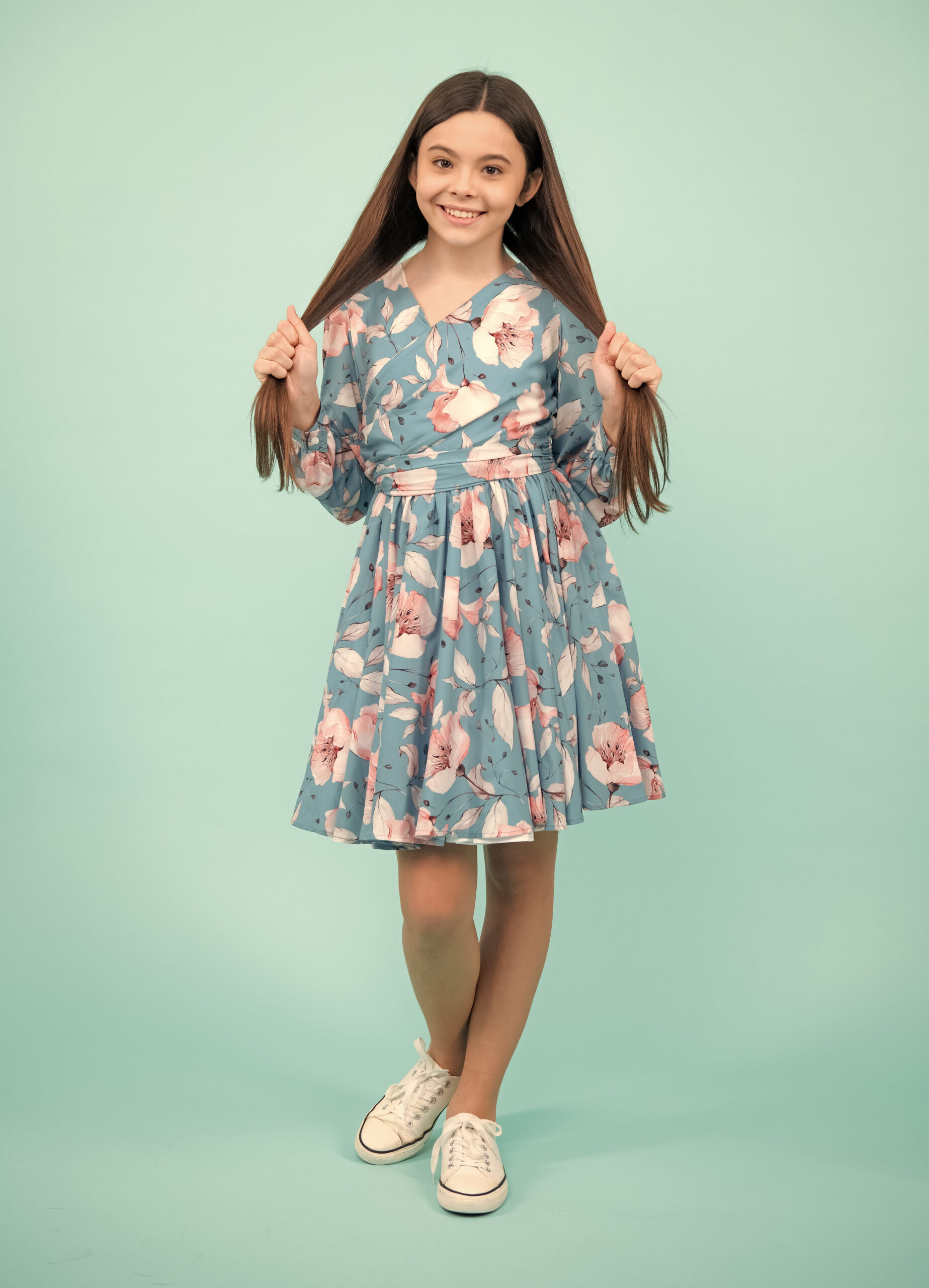 Young graceful teenager child in dress isolated on blue background. Beautiful teen in summer clothing. Happy teenager, positive and smiling emotions